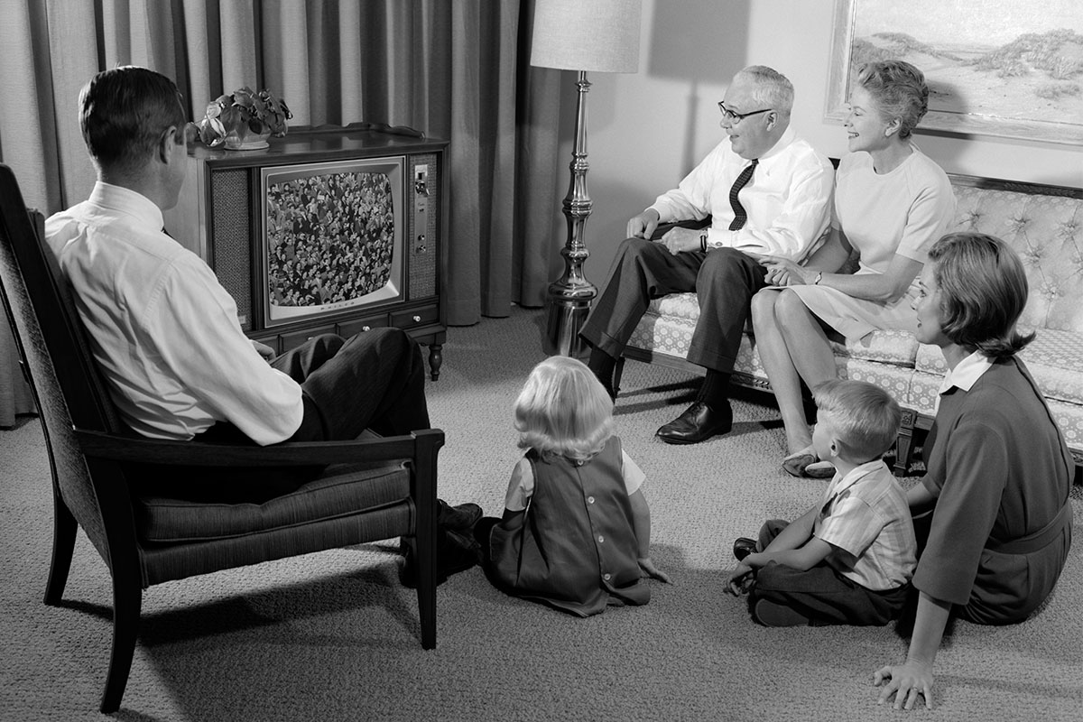 A family sits down around a TV box in the 1950s.