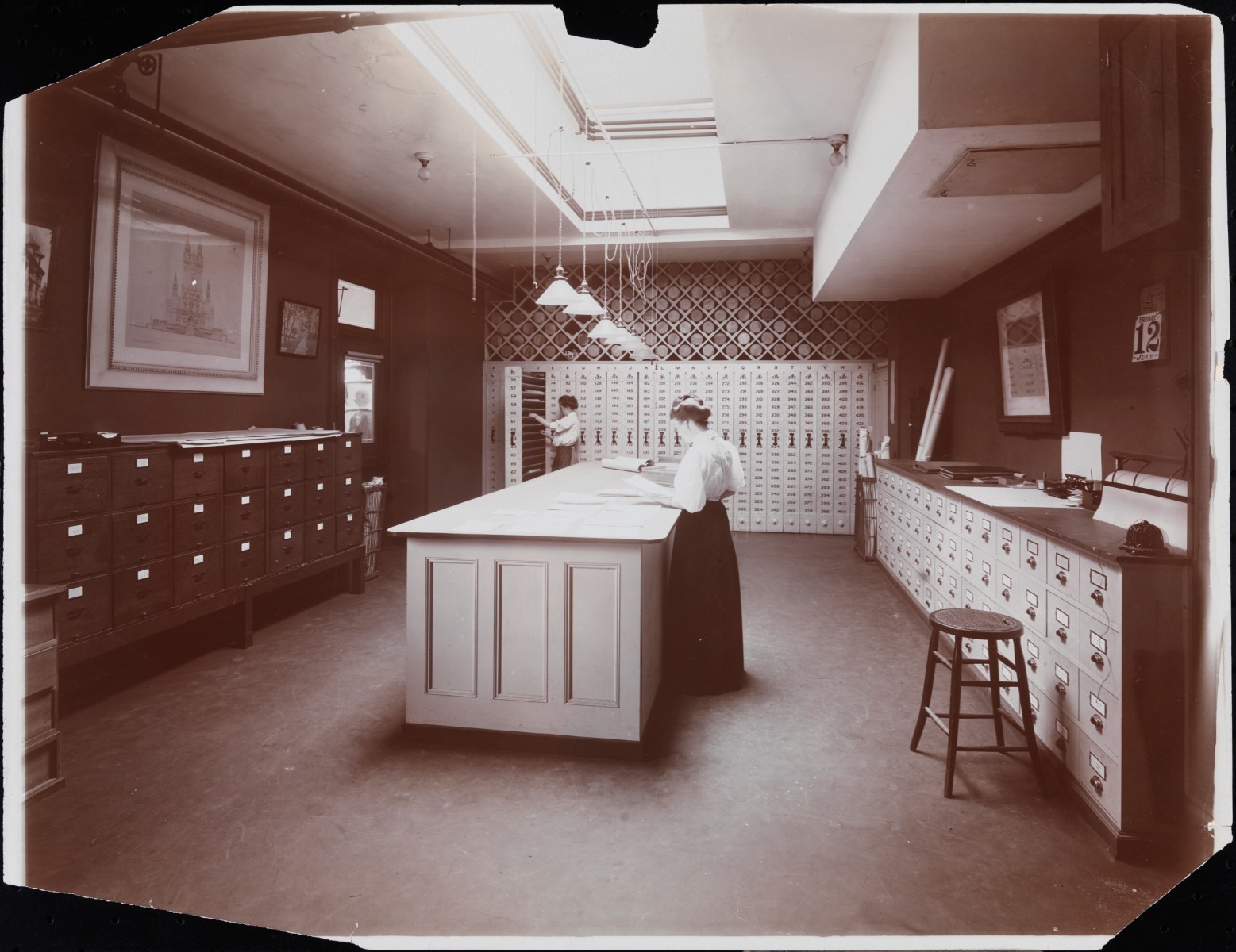 This picture shows the professionalization and scaling up of architecture firms. If you look closely, this is a highly organized room filled with filing systems containing drawings and blueprints around the perimeter. That was high-tech at the time. File drawers and filing systems were really the key tools of the trade then.