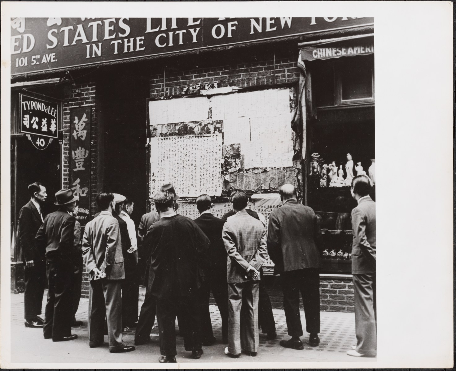 This was the heyday of print journalism and we have a few examples of foreign language papers in New York City. This photo shows people in Chinatown during the Second World War reading news from the war pasted on a wall. When newspapers couldn’t be printed or people didn't have access to them in large numbers, the news would just go up onto a board like this. That was a way in which the news was disseminated at this time.