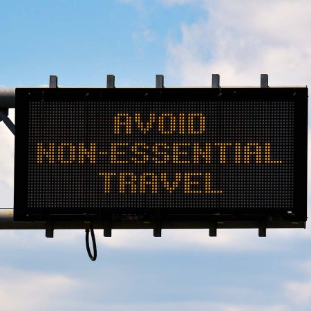 A sign above a road reading "Avoid Non-Essential Travel"
