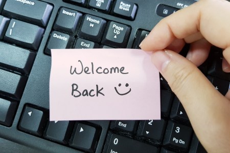 A sticky note held over a keyboard reads "Welcome Back"