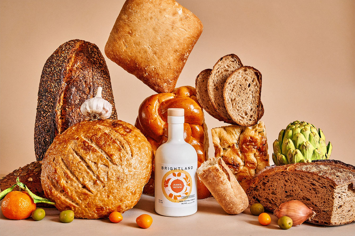a bottle of bright land olive oil surrounded by loaves of bread