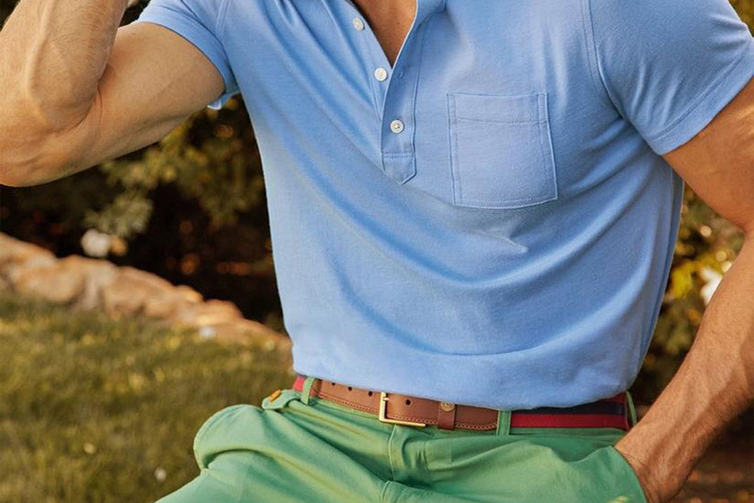 a close up shot of a Brooks Brother model wearing a light blue polo, brown belt, and light green pants