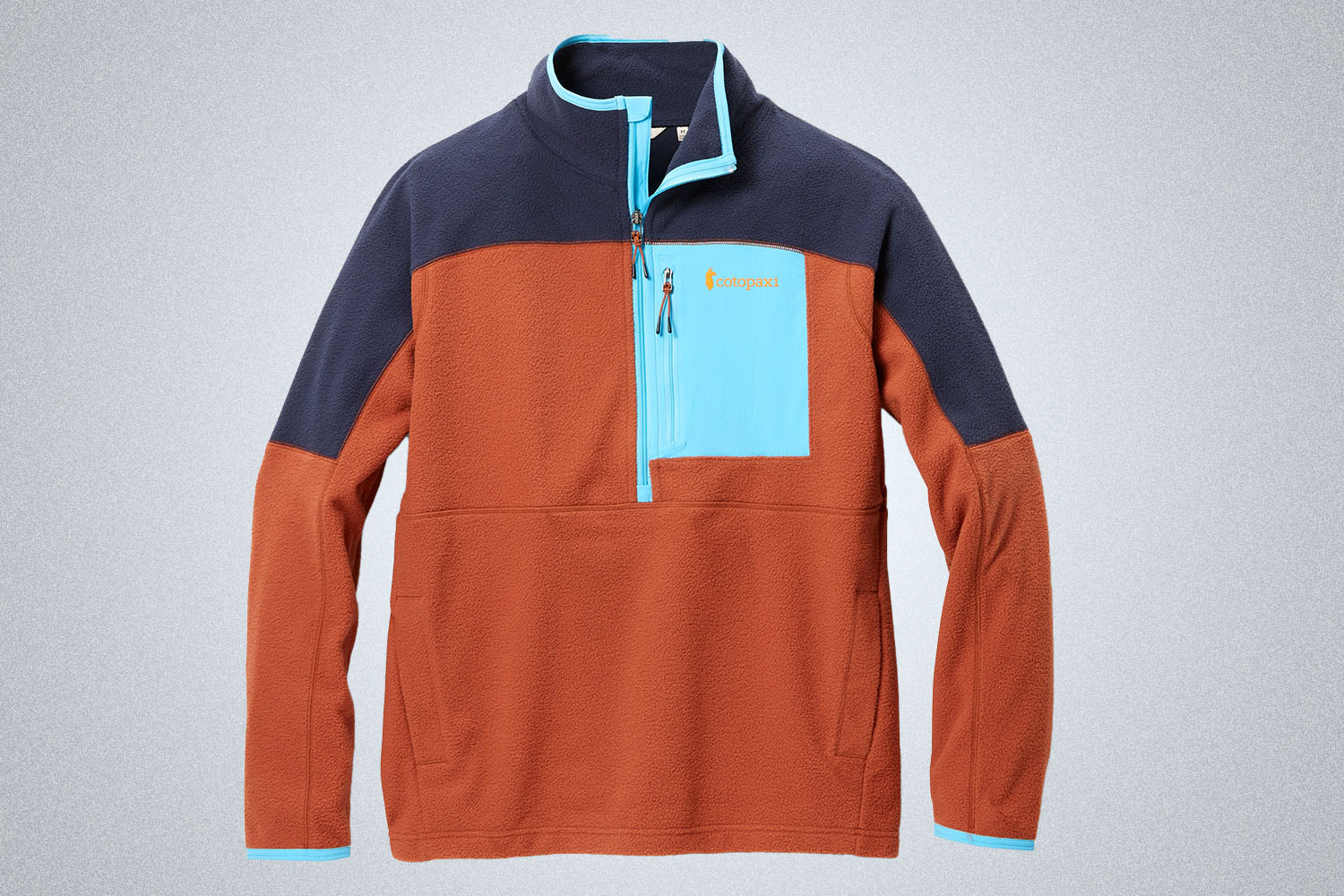 a orange and blue cotopaxi half-zip on a grey background