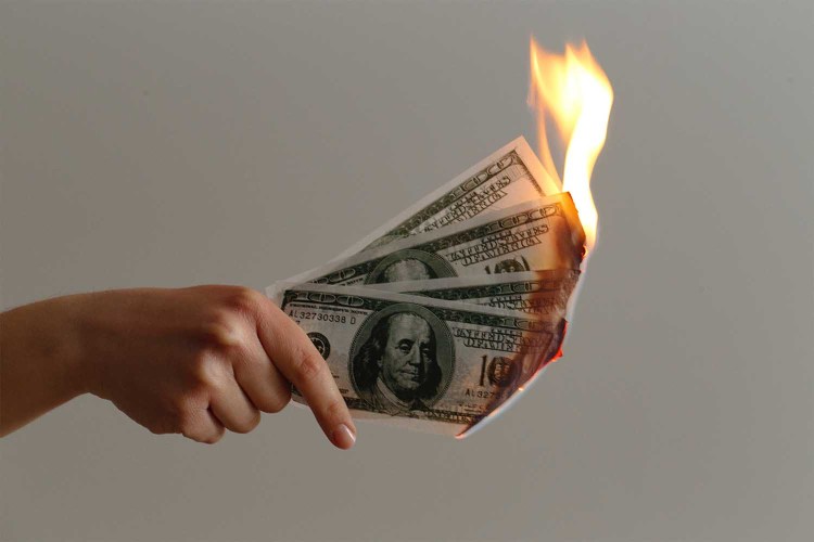 Hand holding money on fire