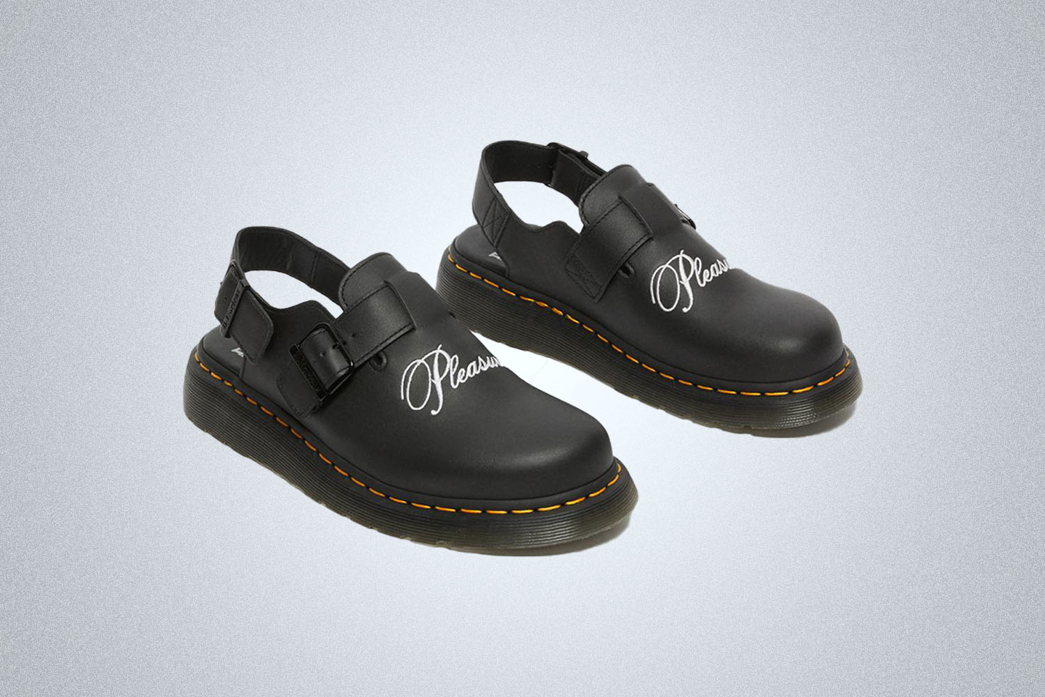 A pair of Dr. Martens x Pleasures mules on a grey background