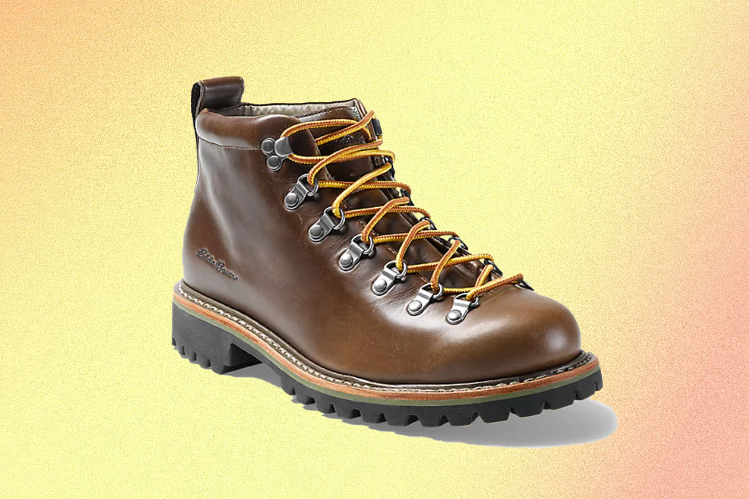 A brown leather hiking boot on a yellow tinged background