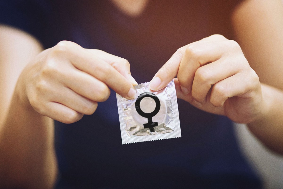 Close up photo shows a person opening a condom wrapper with a female symbol on it