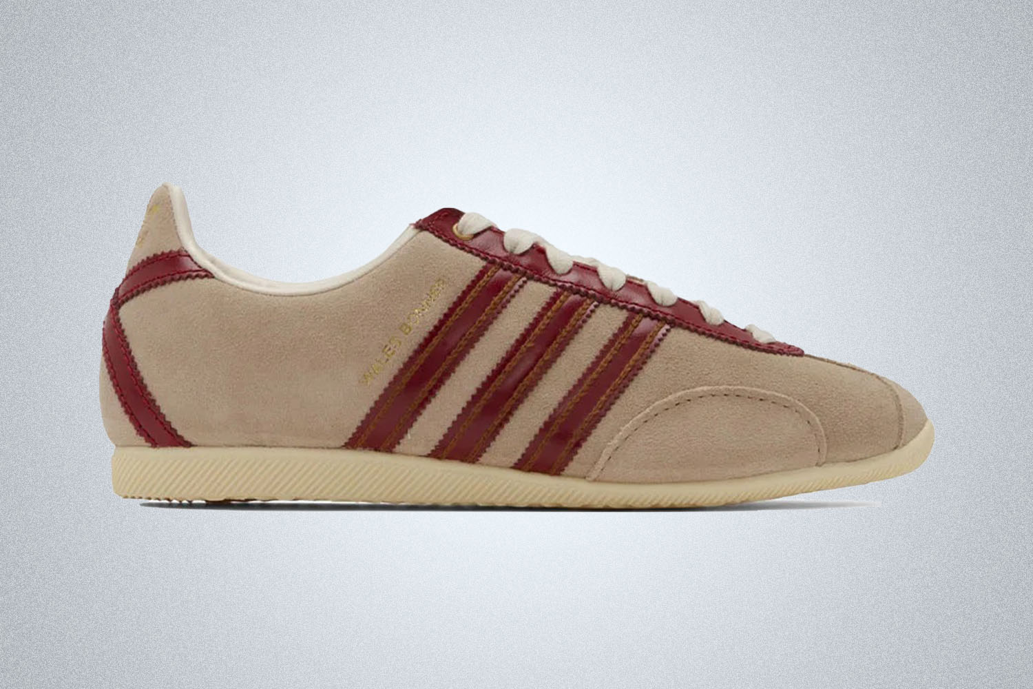 a pair of beige and maroon Adidas x WB sneakers on a grey background