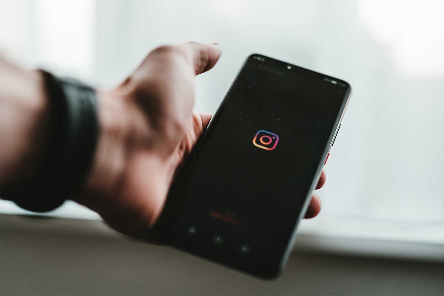 A person holding an iPhone with the Instagram logo.