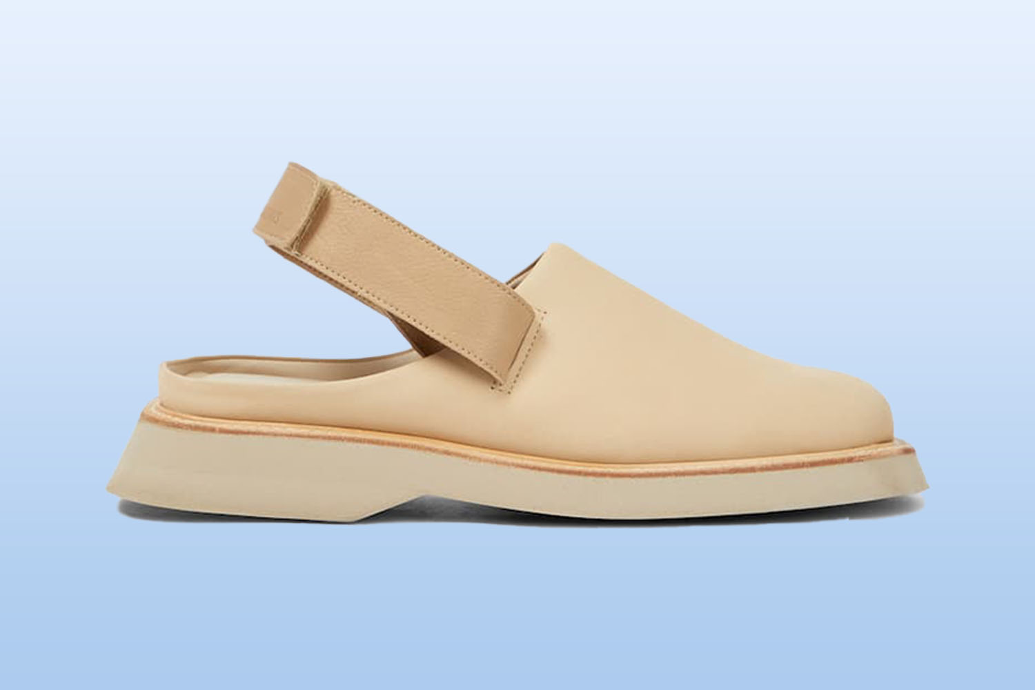 A pair of beige leather mules from mytheresa on a light blue background