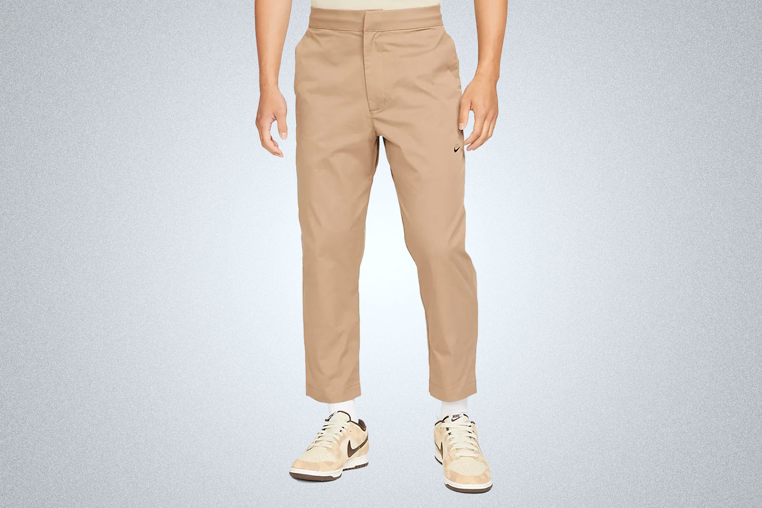 a pair of cropped Khaki nike pants on a grey background