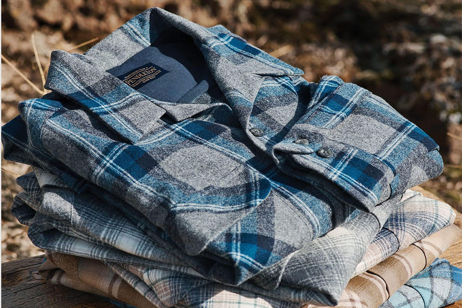 A stack of Pendleton flannels on a beach
