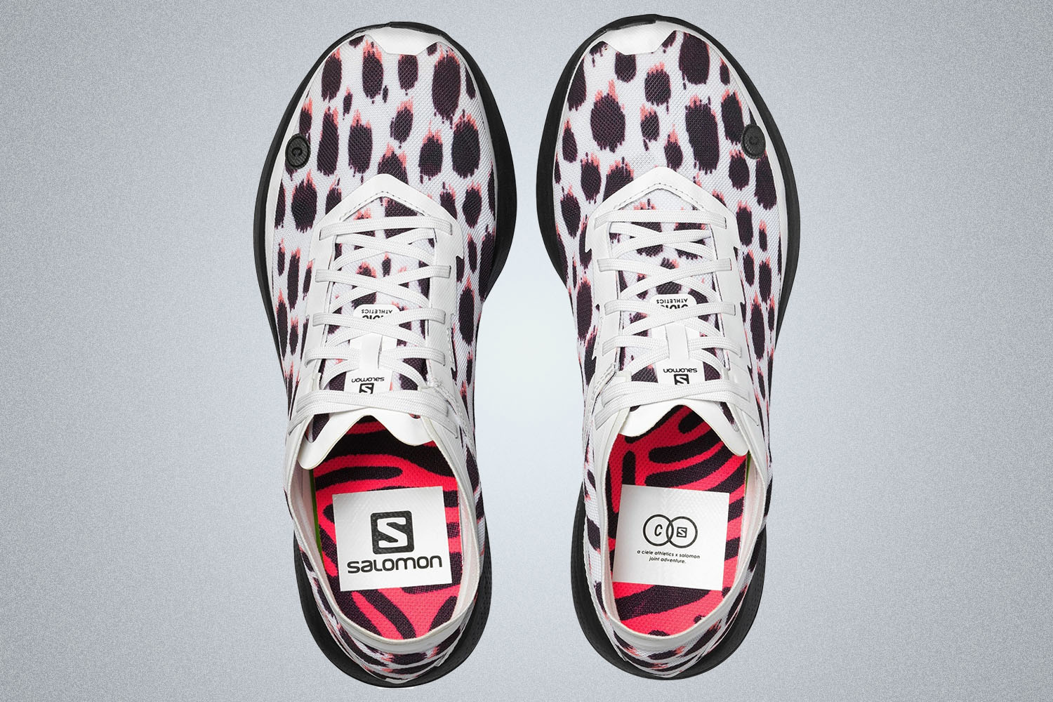 a pair of colorful white and red spotted runners from Salomon on a grey background