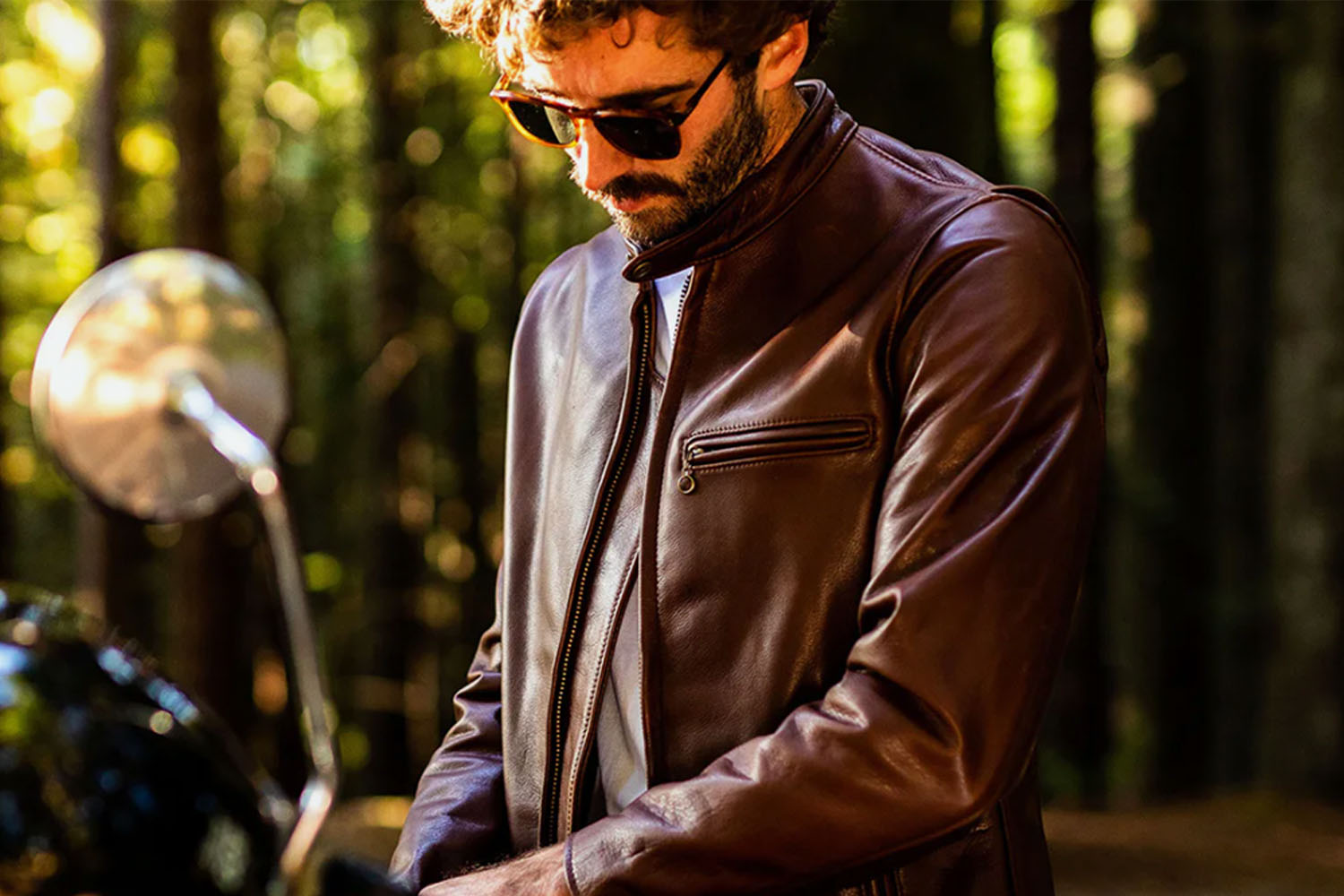 A man in a Schoot leather jacket on a motorcycle