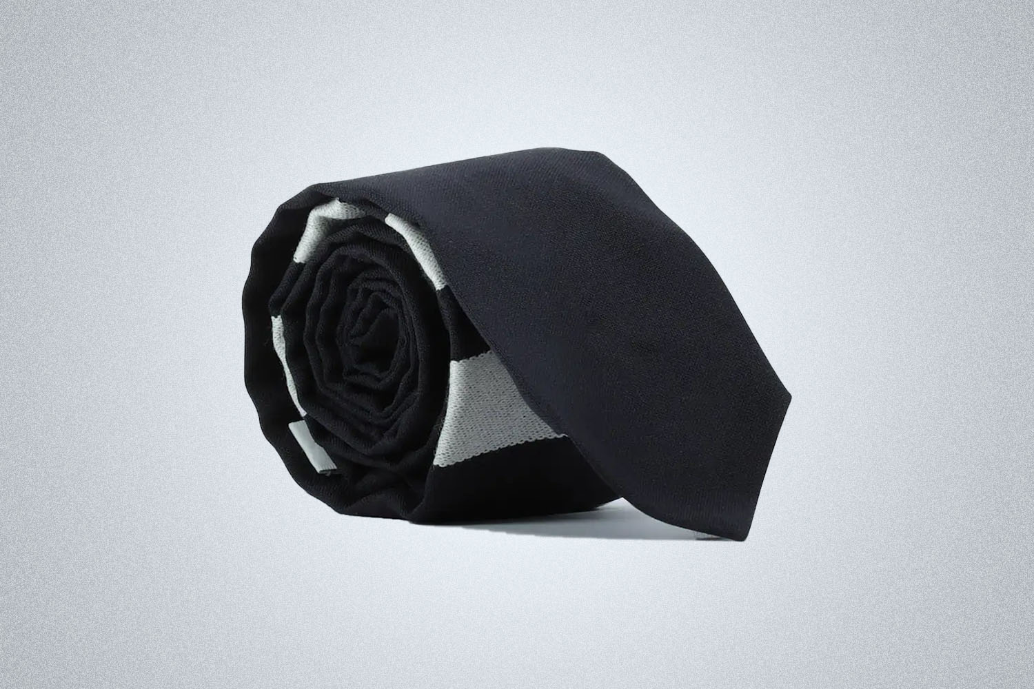 a rolled-up Thom Browne tie on a grey background