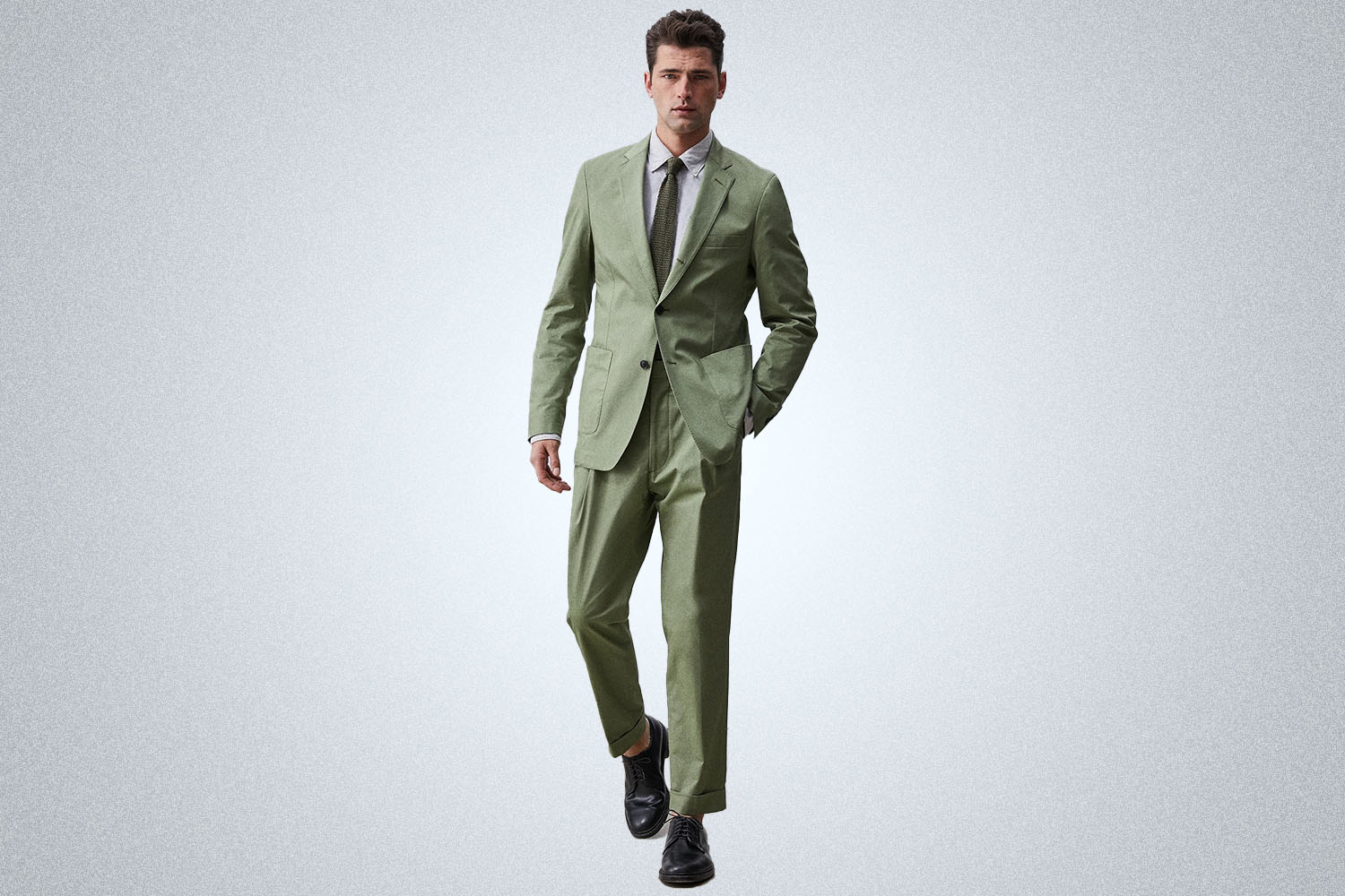 A model in a green Todd Snyder suit on a grey background