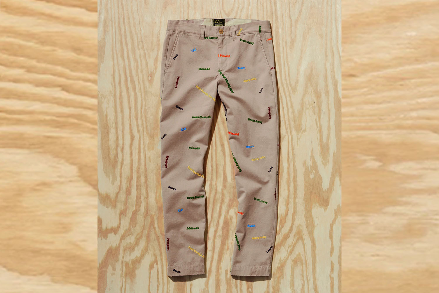 a Todd Snyder x L.L. Bean pair of Embroidered Pants on a wooden background