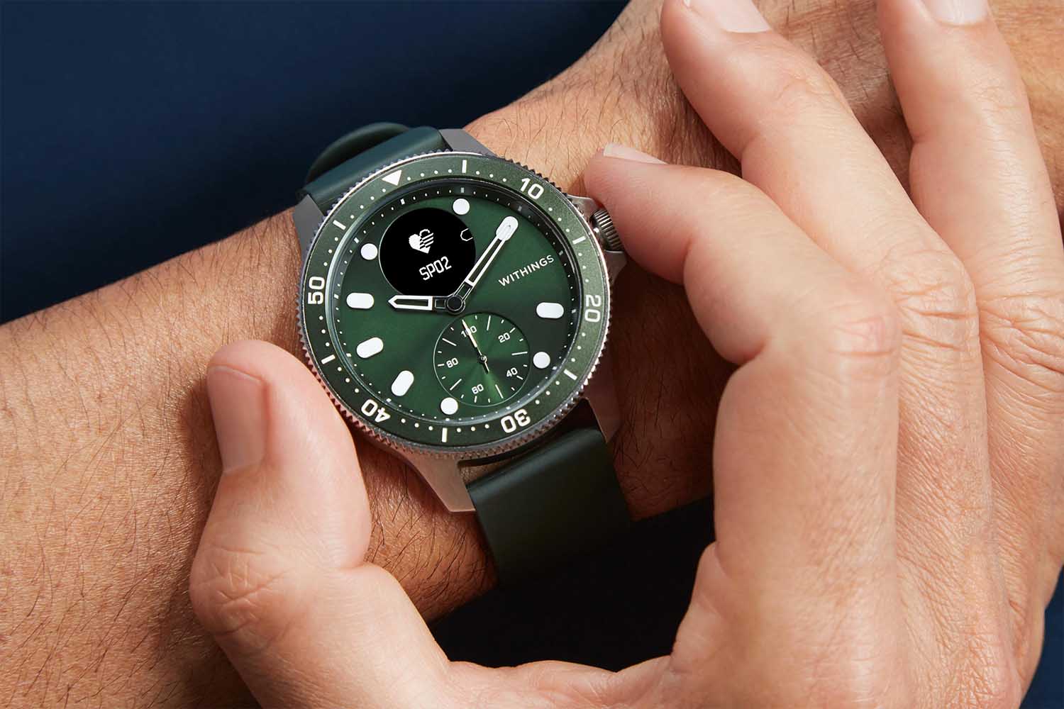 a smartwatch with a green face on a models wrist from the brand WITHINGS