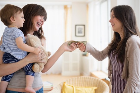 woman passing other woman money with baby in arms