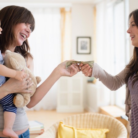 woman passing other woman money with baby in arms