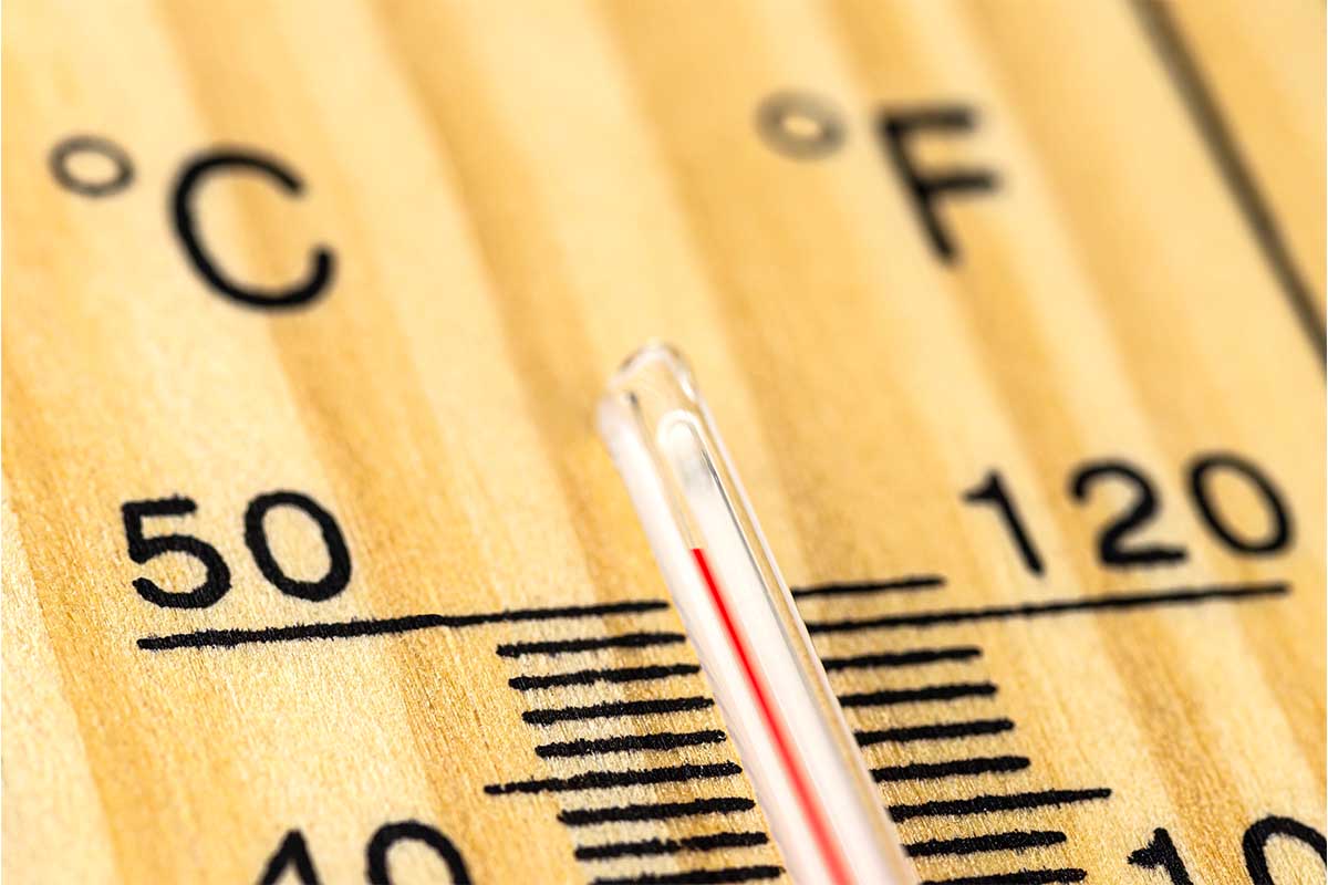 a classic wooden thermometer showing a temperature over 50 degrees Celsius, 122 degrees Fahrenheit.