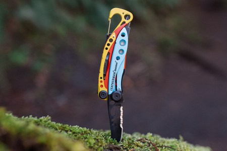 The Leatherman x Topo Designs Skeletool sticking into a log with the knife down. The multitool may be the best-looking Leatherman ever made.