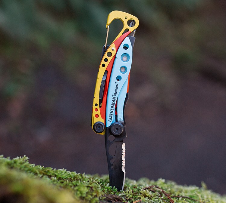 The Leatherman x Topo Designs Skeletool sticking into a log with the knife down. The multitool may be the best-looking Leatherman ever made.