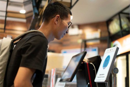 Asian man is using face to make payment on machine - stock photo