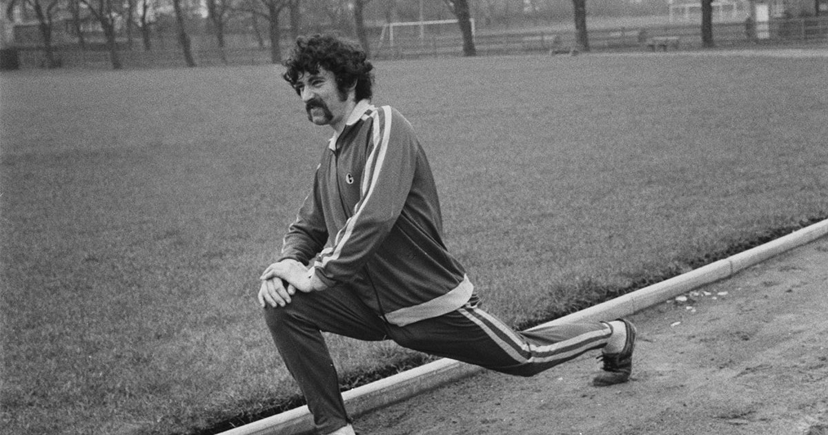 A man stretching on a track in black and white. Here's how you can bulletproof your body.