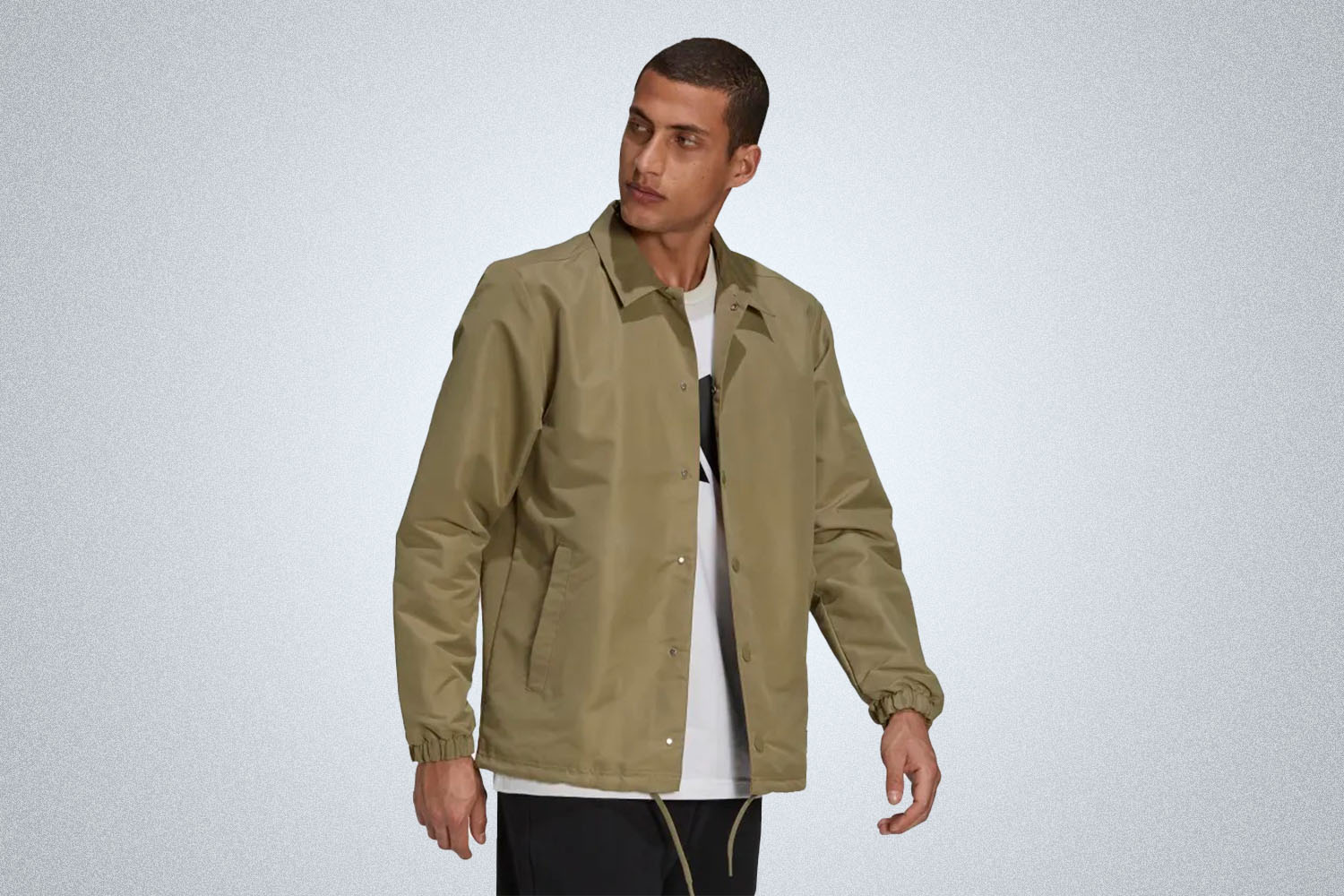 a model in a beige-green coaches jacket from Adidas on a grey background