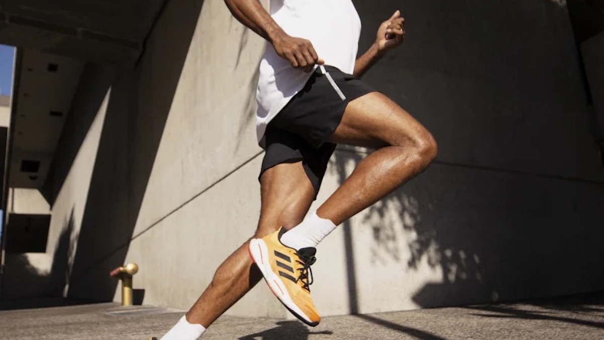 a model in Adidas gear running on concrete