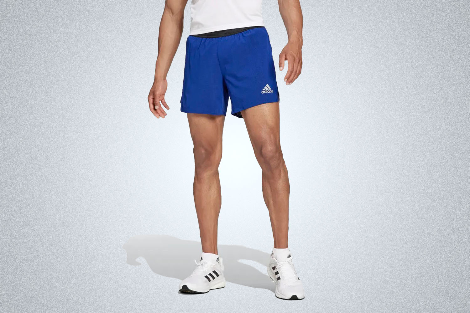 a model in a pair of blue running shorts from Adidas on a grey background