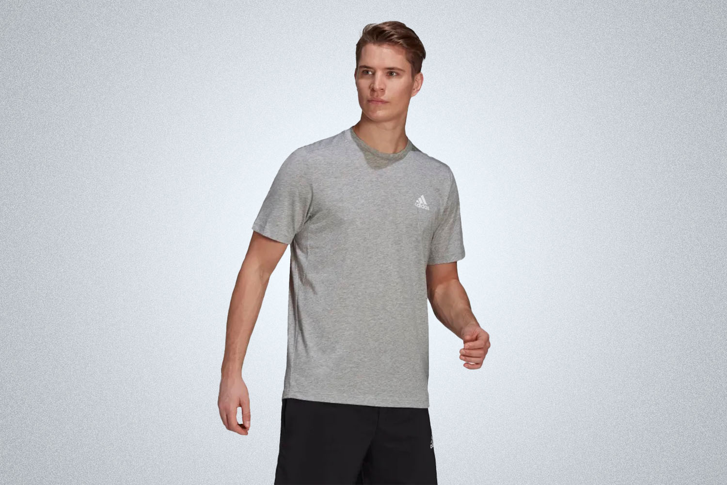 a model in a grey crewneck tee from Adidas on a grey background