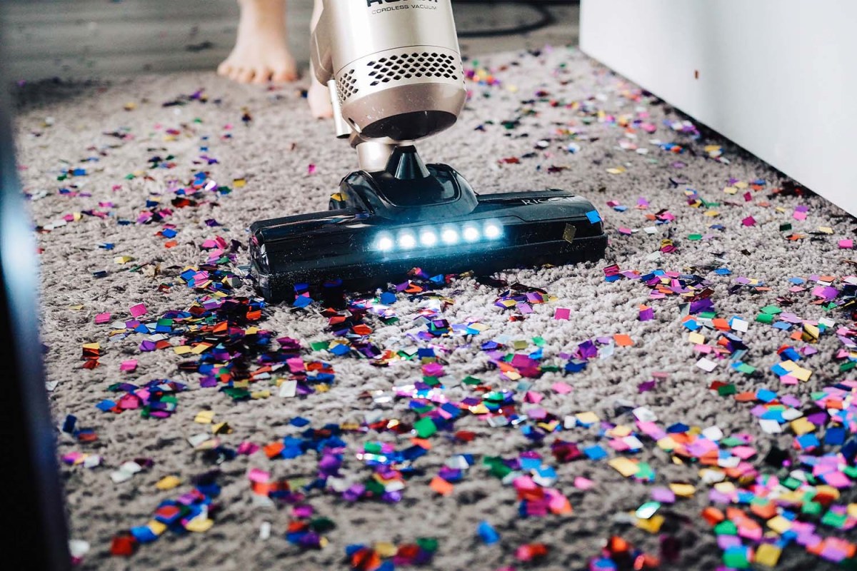 Remnants of a party being vacuumed up, including multicolored glitter strewn across the floor