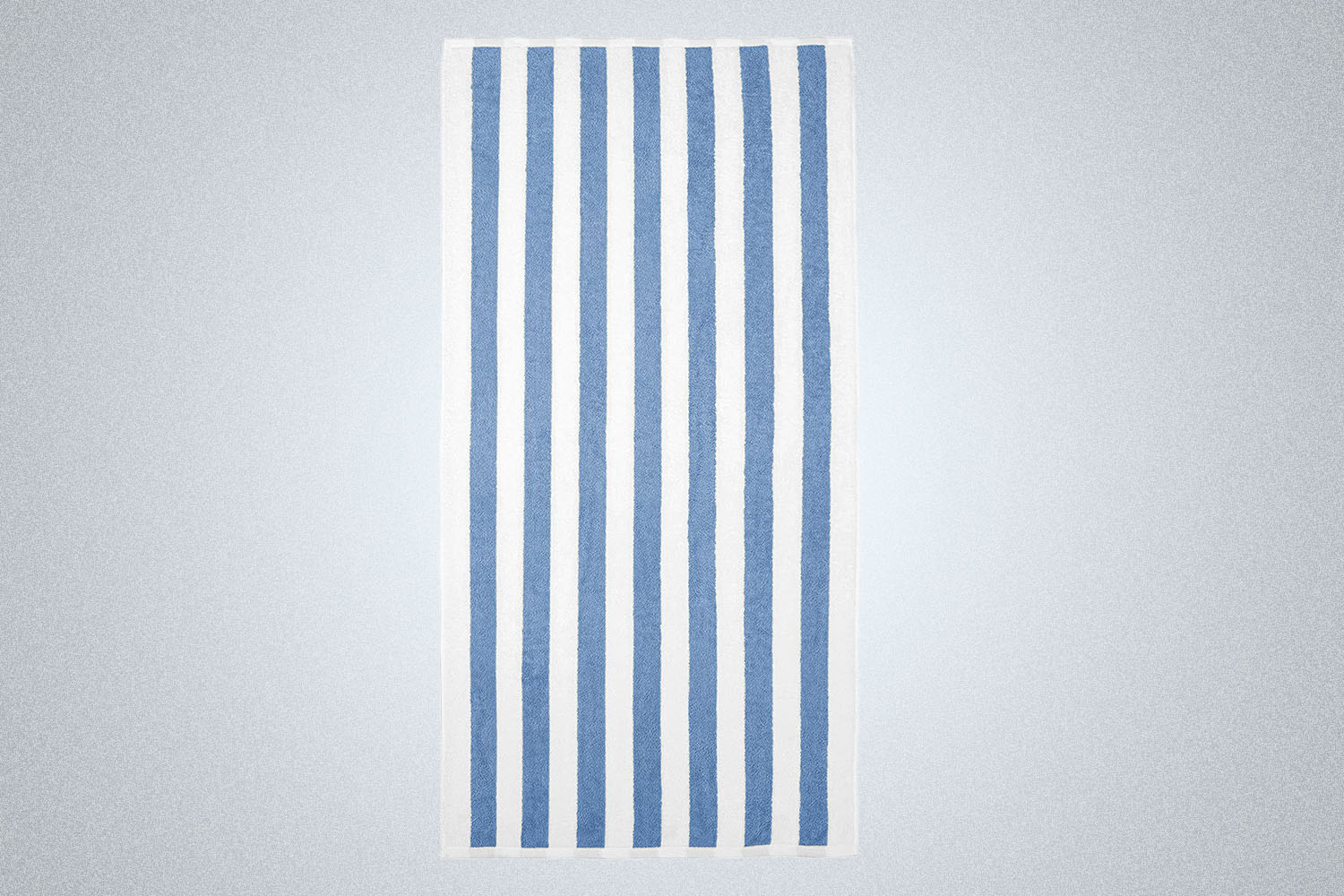 a white and blue striped beach towel from Amazon on a grey background