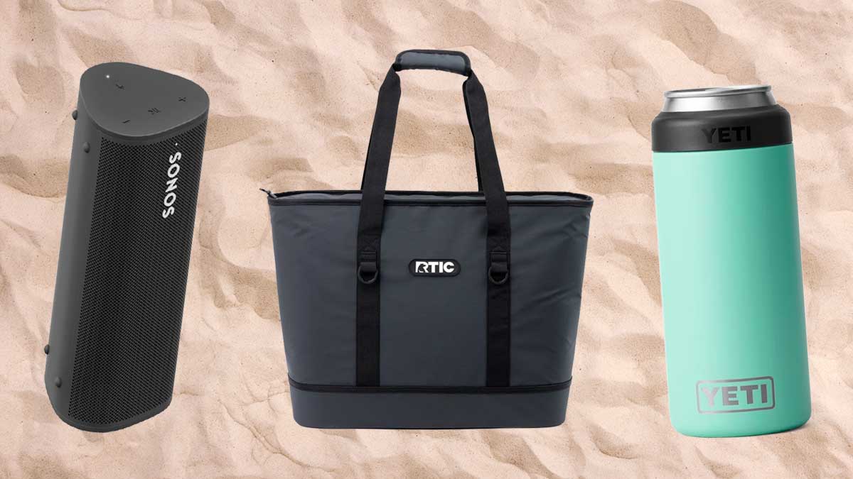 A Sonos Roam speaker, RTIC insulated tote bag and Yeti can insulator, all pictured on a sandy beach background