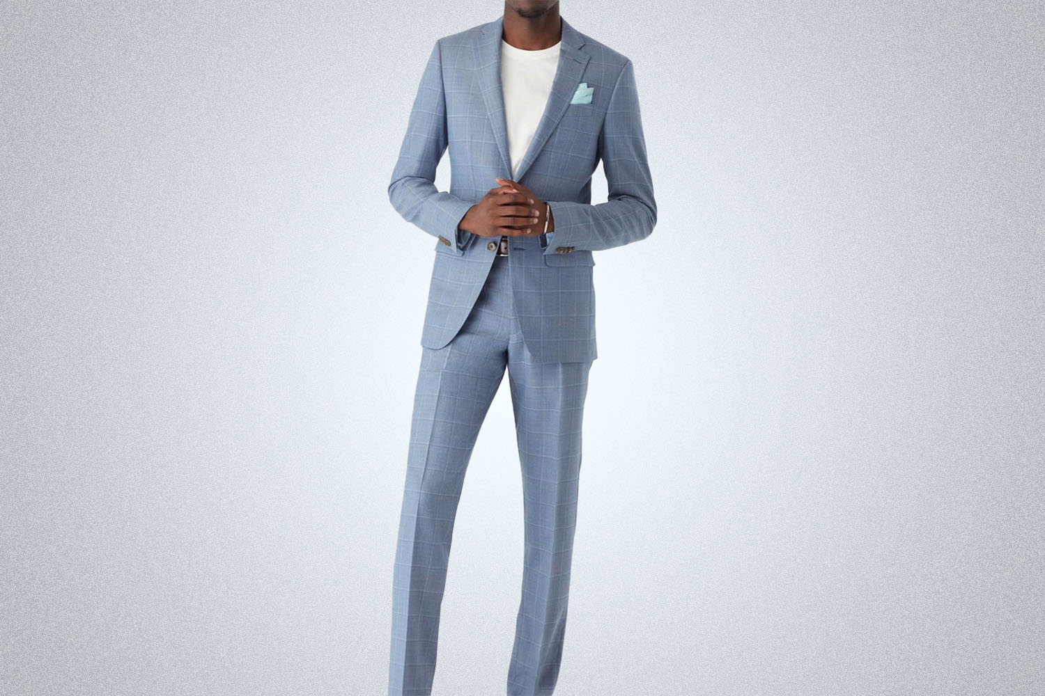 a model in a light blue striped Indochino suit on a grey background