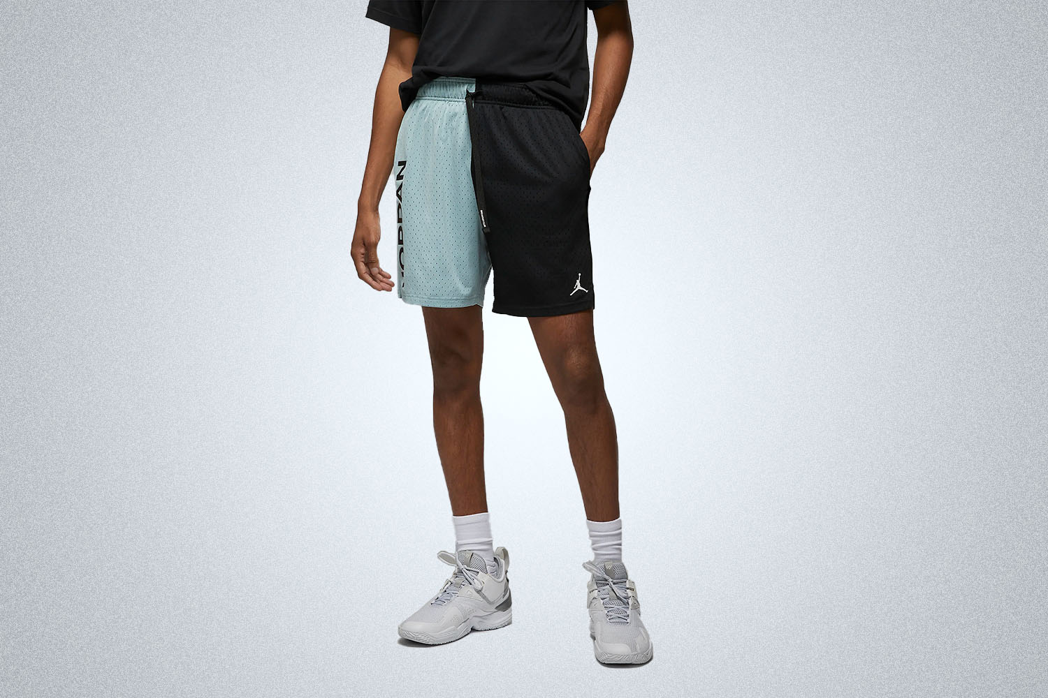 a model in two-toned blue and black Nike Jordan shorts on a grey background