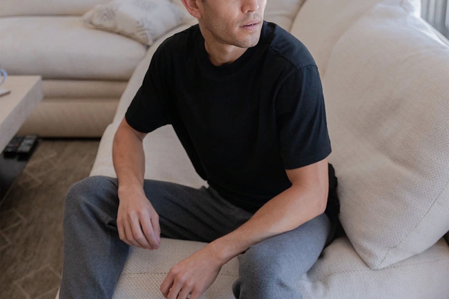 a model in a black Lagho shirt on a couch