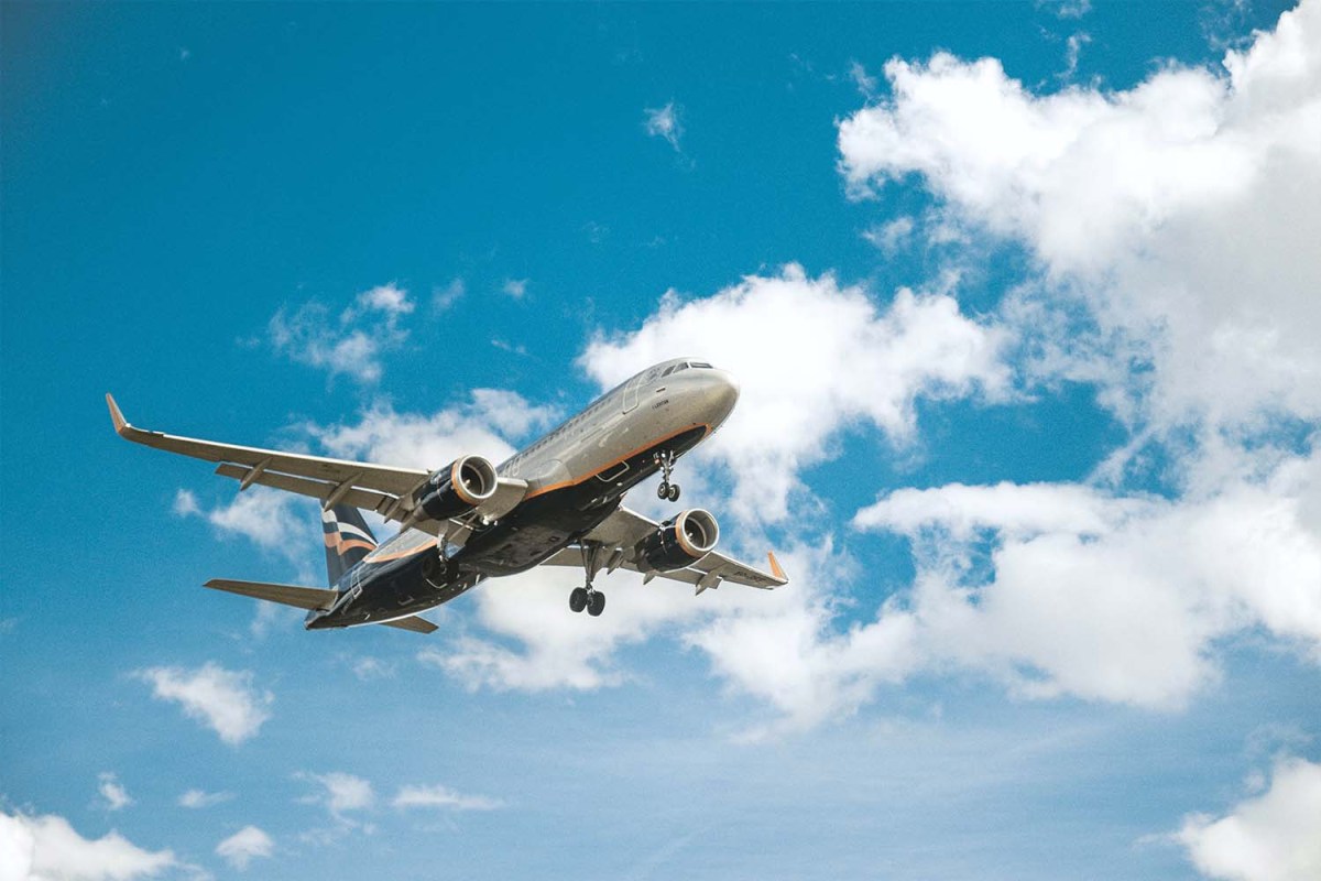 An airplane flying with a blue sky and white clouds in the background. We take a look at the new monkeypox travel advisory issued by the CDC and what it means for American travelers.