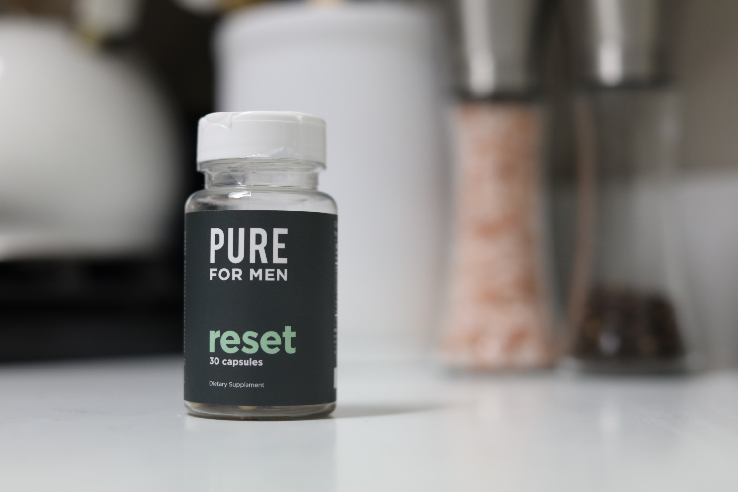 A bottle of Pure for Men's Reset cleanse pills sits on a kitchen countertop