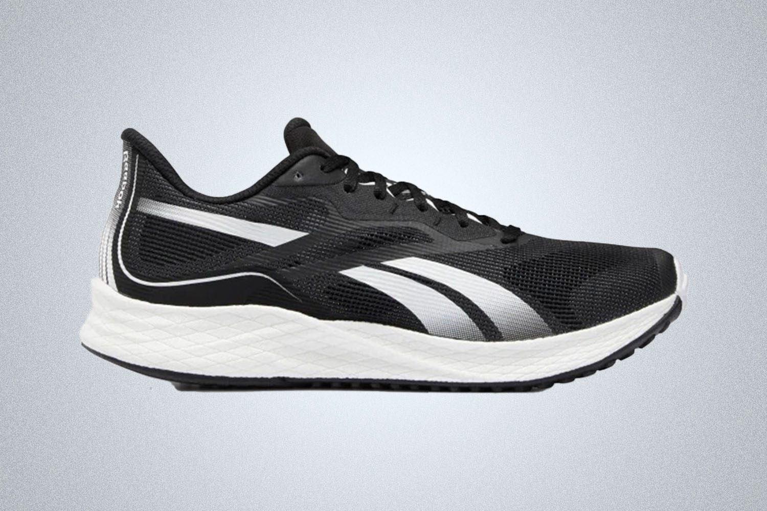 A pair of black and white accented Reebok running shoes on a grey background