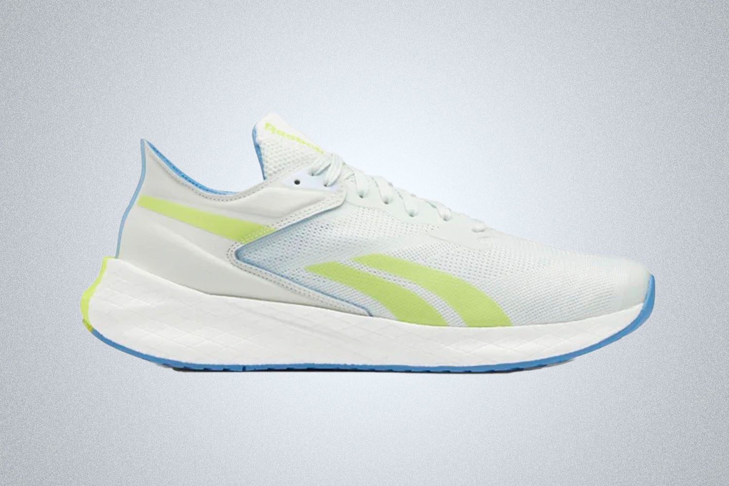A pair of white and green accented Reebok running shoes on a grey background