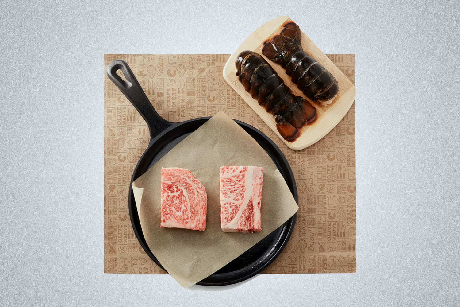 a plate of surf and turf items on a wooden block on a grey background