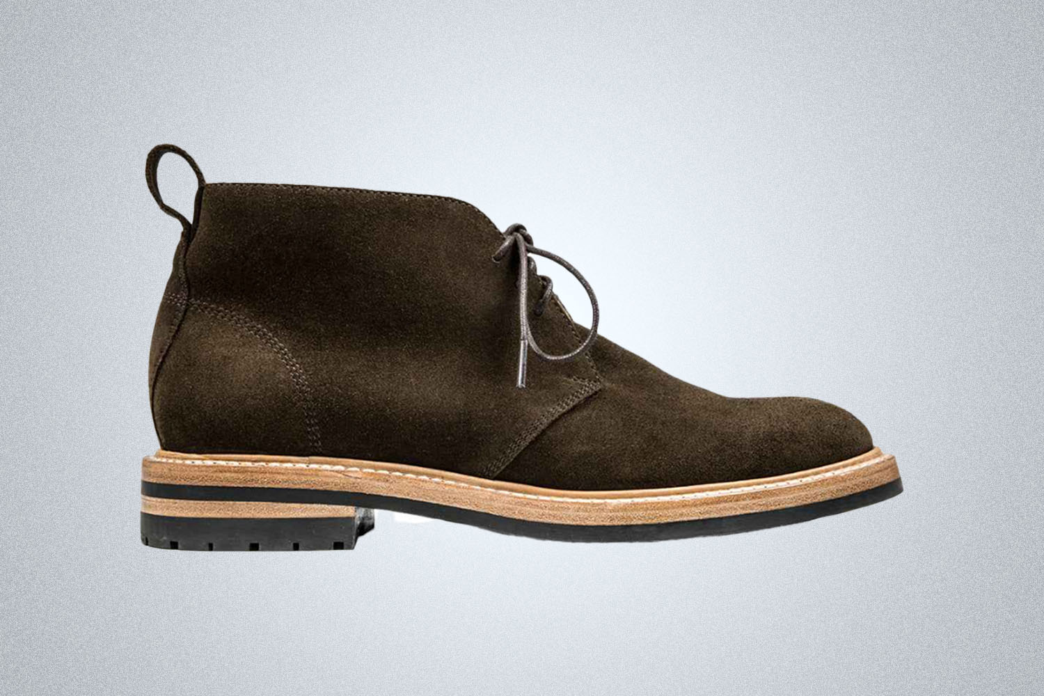 a dark brown suede chukka boot with wooden midsole and vibram rubber sole from Taylor Stitch on a grey background