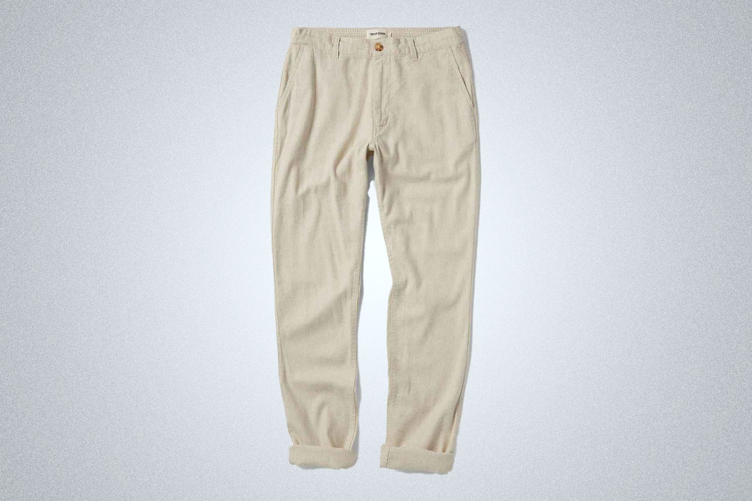 a pair of beige drawstring pants from Taylor Stitch on a grey background