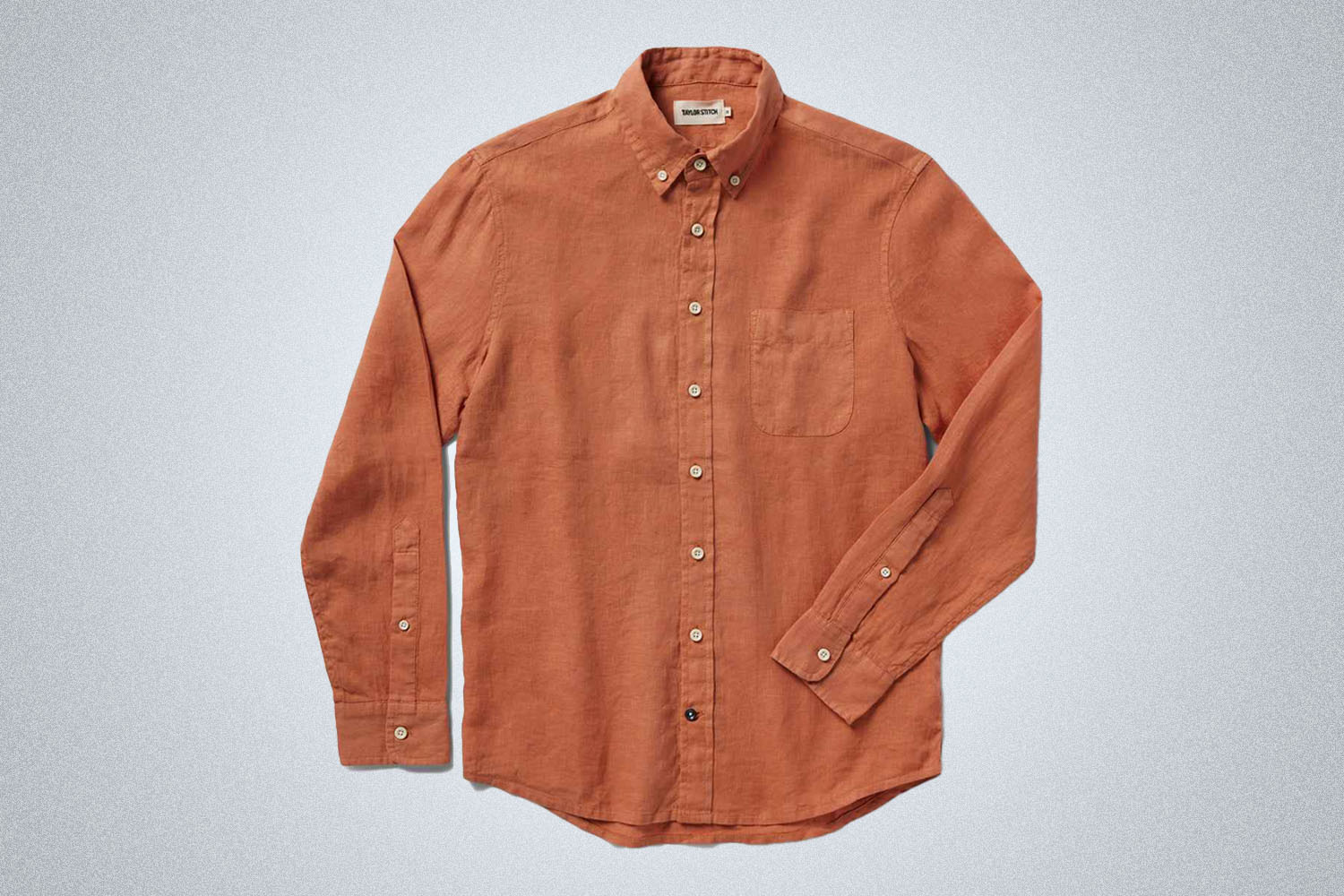 a apricot orange long sleeve linen button up shirt from Taylor Stitch on a grey background