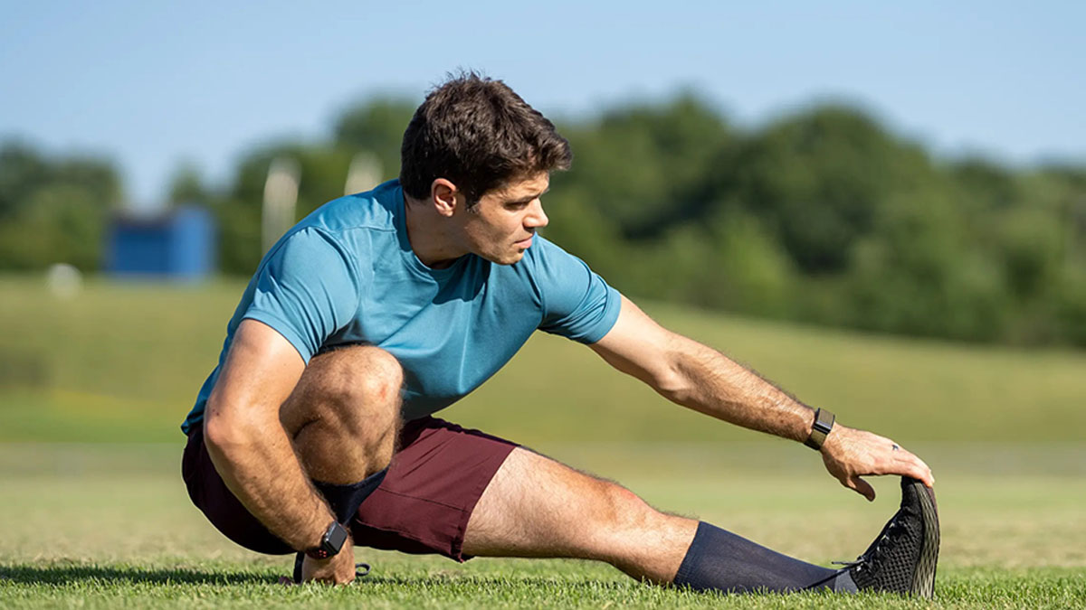 a model stretching on grass in the Ten Thousand maroon Interval Shorts
