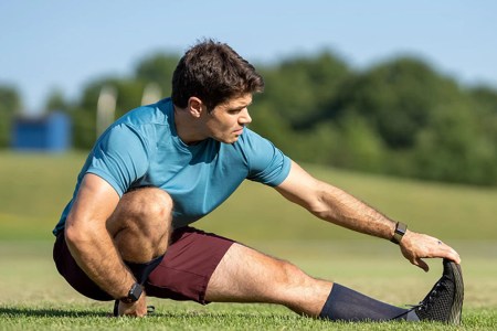 a model stretching on grass in the Ten Thousand maroon Interval Shorts